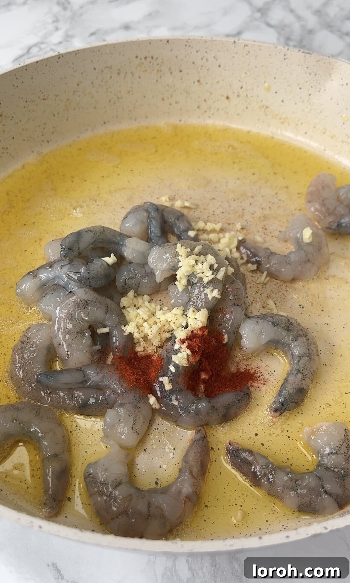 Sizzling garlic prawns cooking in a frying pan, ready to top the risotto.