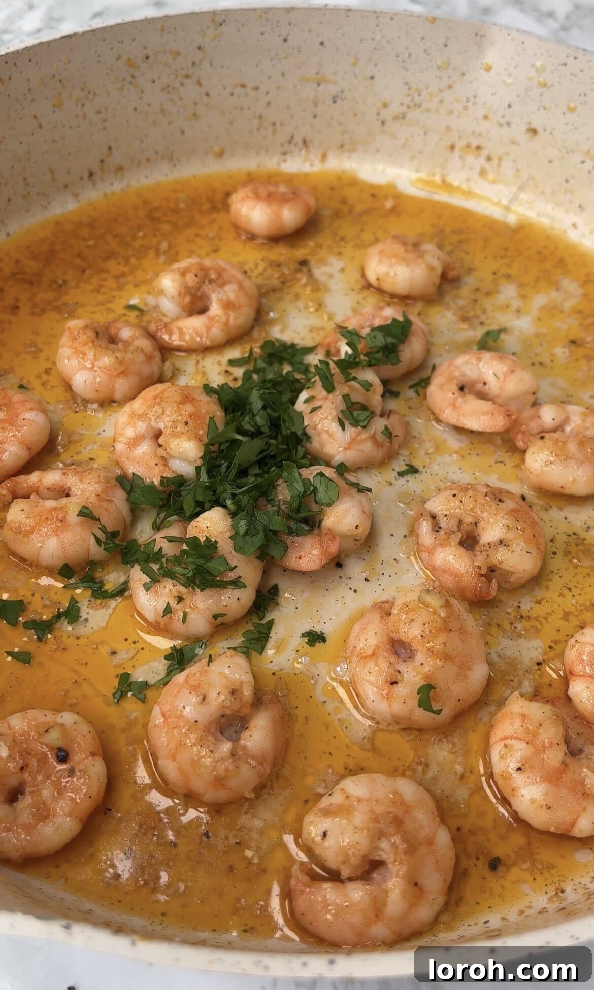 Adding freshly chopped parsley and a squeeze of lemon to the cooked garlic prawns.