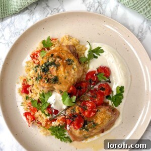 Crispy oven-roasted garlic butter chicken thighs served with a colorful warm bulgur wheat salad