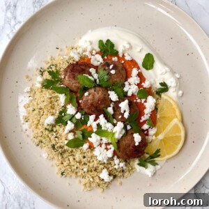 Succulent Lightly Spiced Lamb Meatballs with vibrant Muhammara, creamy Feta, and aromatic Herby Couscous – a perfect Mediterranean dinner idea.