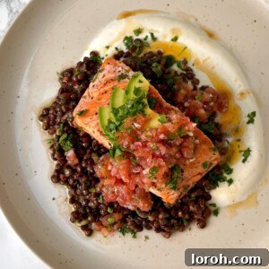 Crispy Butter Sizzled Salmon with vibrant Herby Chilli Lentils, creamy Garlicky Yogurt, and fresh Tomato Salsa, garnished with herbs and lemon.
