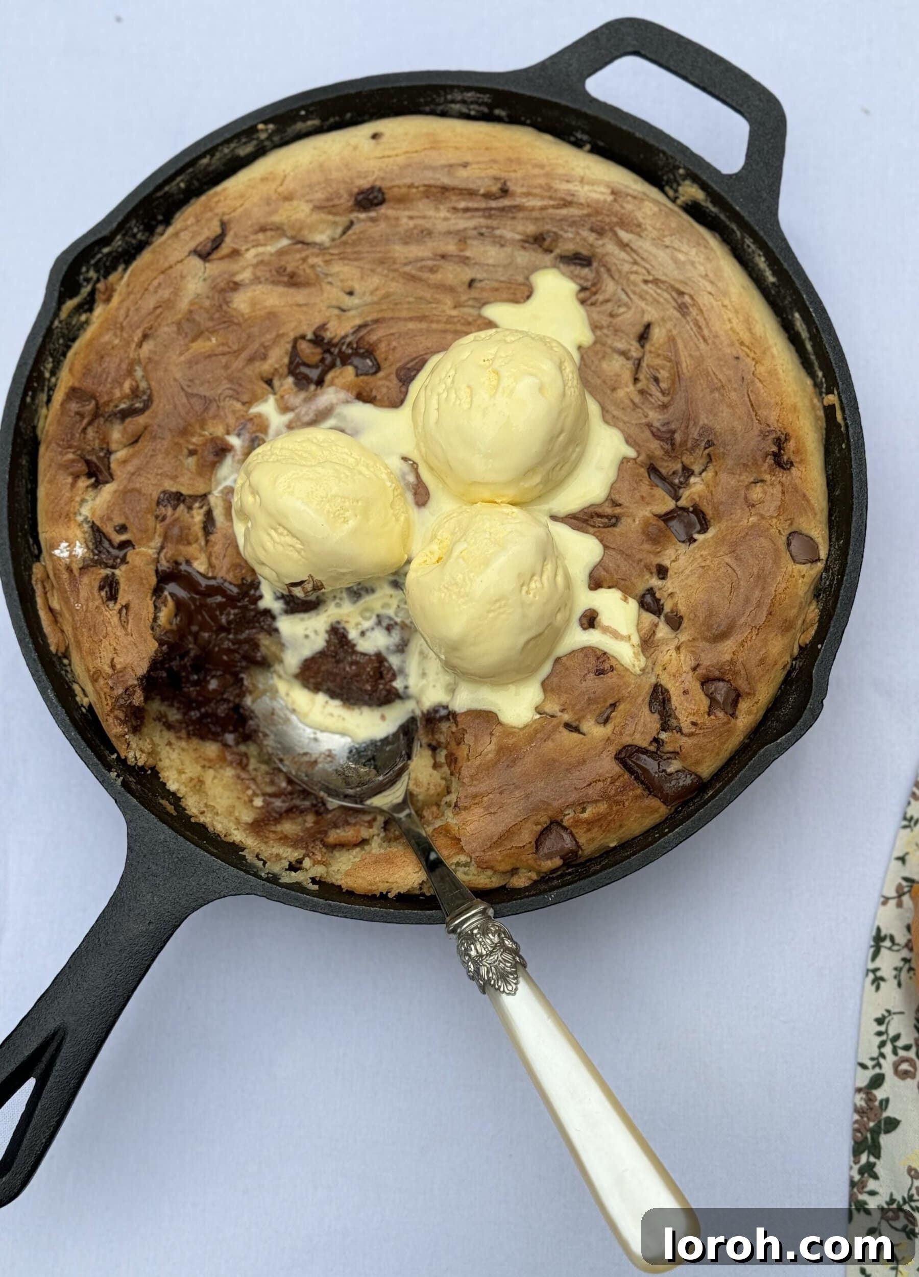 Effortless Condensed Milk Cookie Bars 11 Close-up of a slice of Chocolate Chip Skillet Cookie with melting vanilla ice cream and fresh raspberries.