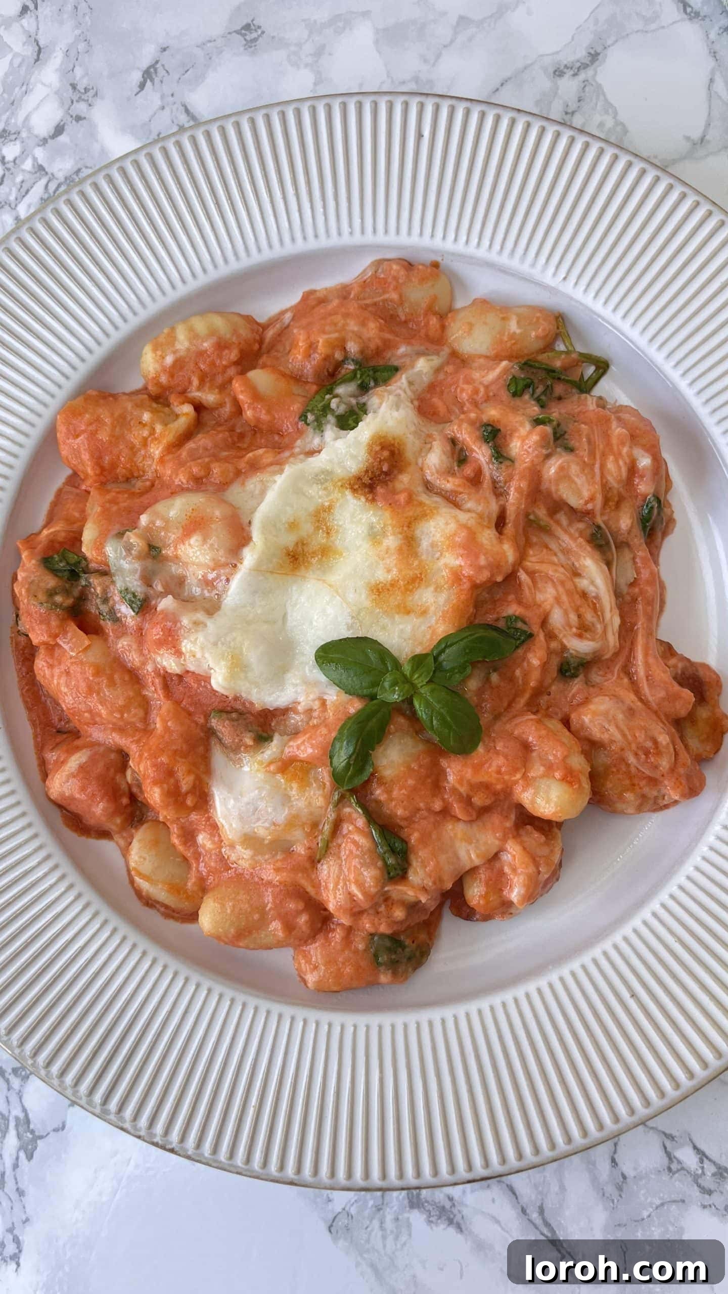 Cheesy Tomato Baked Gnocchi on a plate with fresh basil on top, ready to be served