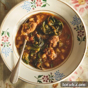 Vintage bowl of sausage and bean stew on a red floral tea towel.