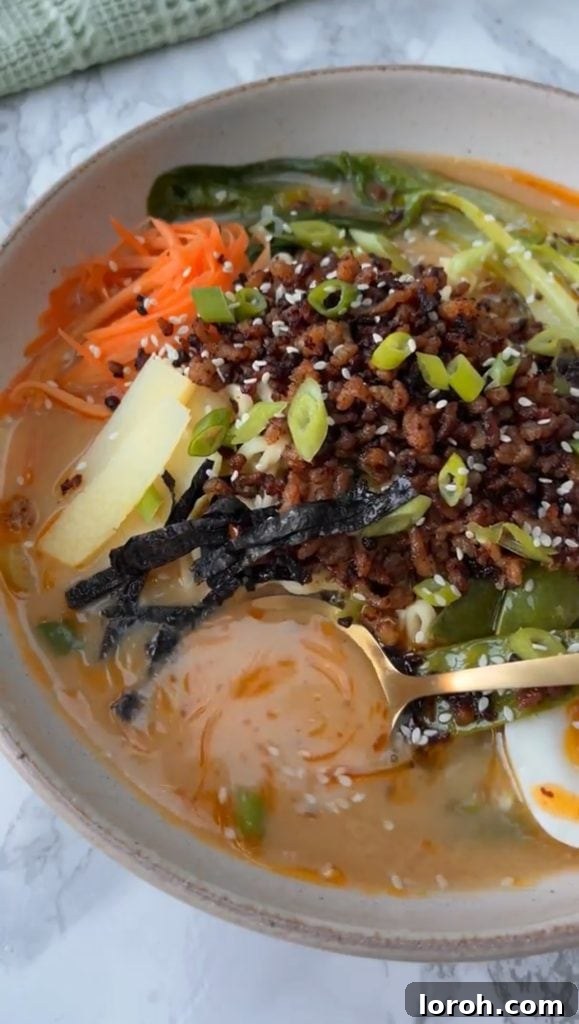 A spoon stirring the rich and flavorful pork ramen broth, showing its creamy texture