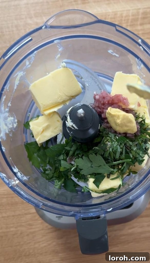 Close-up of fresh tarragon, parsley, chopped shallots, and softened butter being added to a blender, illustrating the simple process of making bearnaise butter for the rib eye steak sandwich.