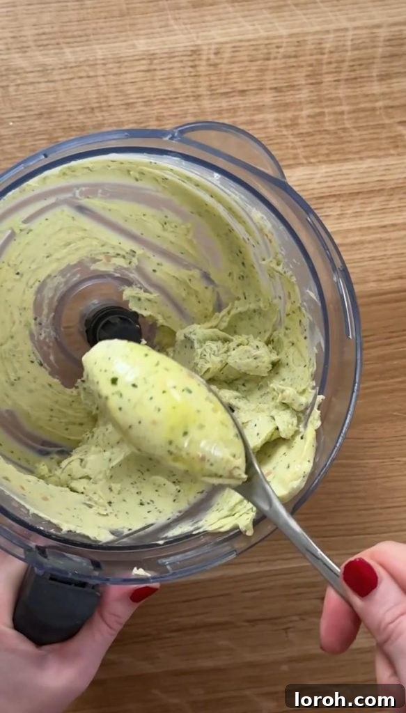 A bowl filled with freshly blended, vibrant green bearnaise butter, perfectly smooth and creamy, ready to be spread onto the focaccia for the ultimate steak sandwich.