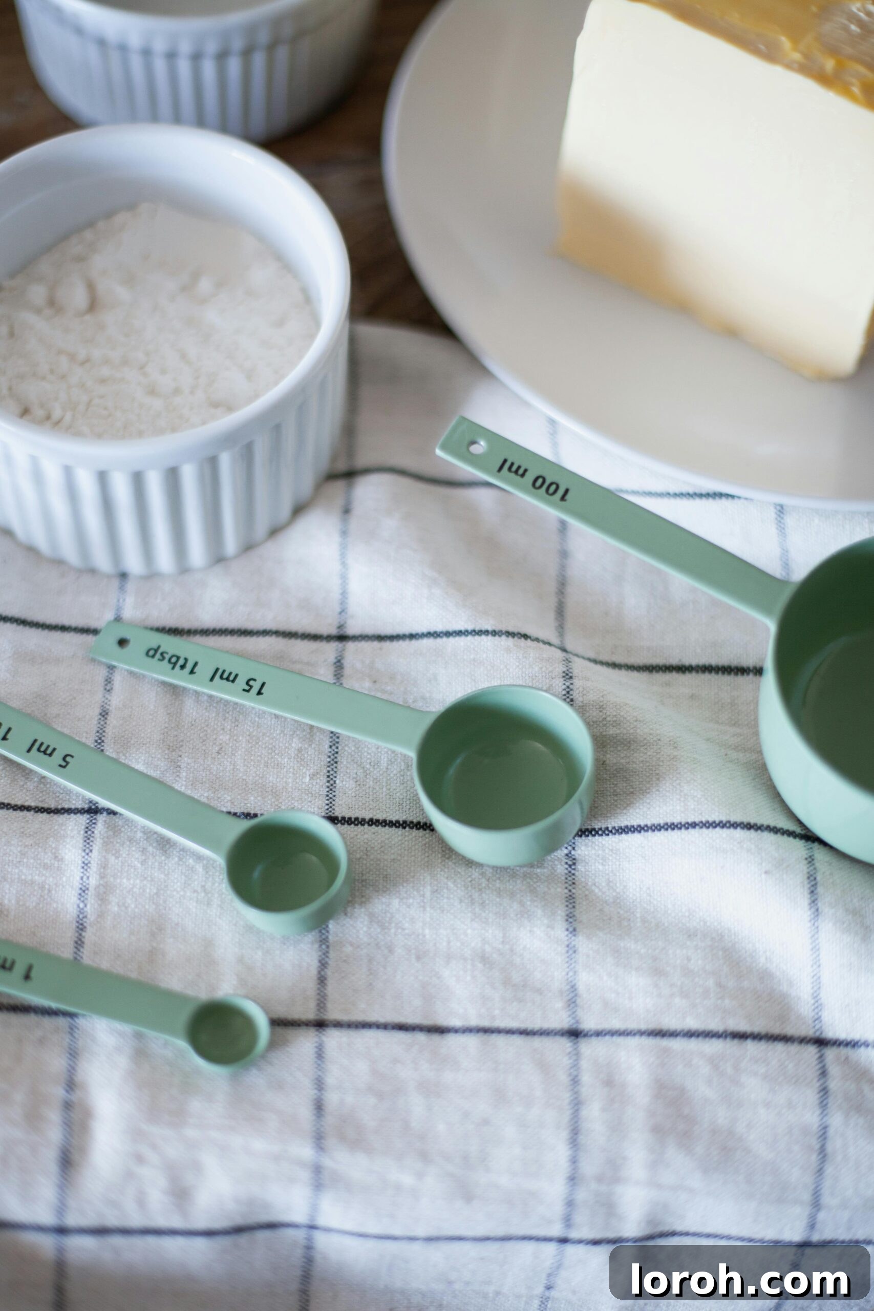 Ounces in a Cup Dry and Liquid Explained 4 measuring cups on a tea towel with ounces of flour before.