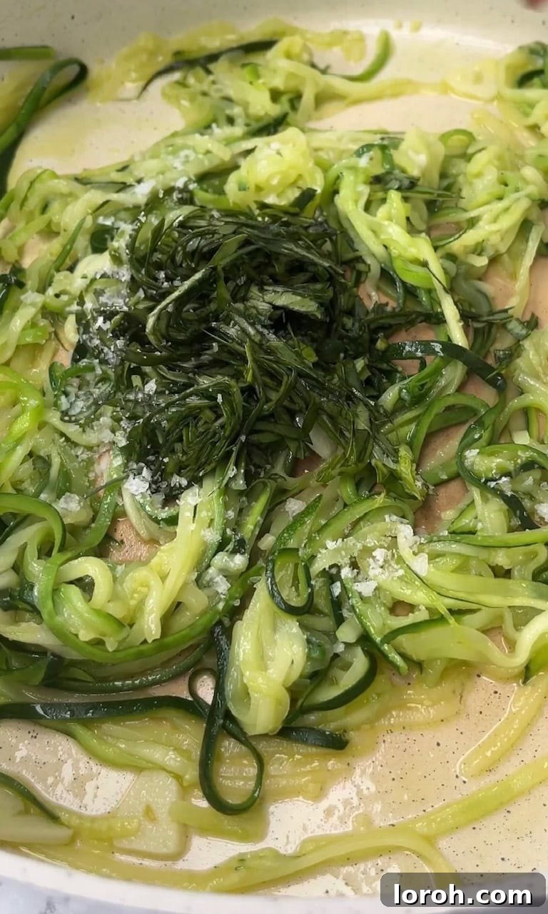 Adding fresh basil to the cooked courgettes in a pan, ready for pasta.