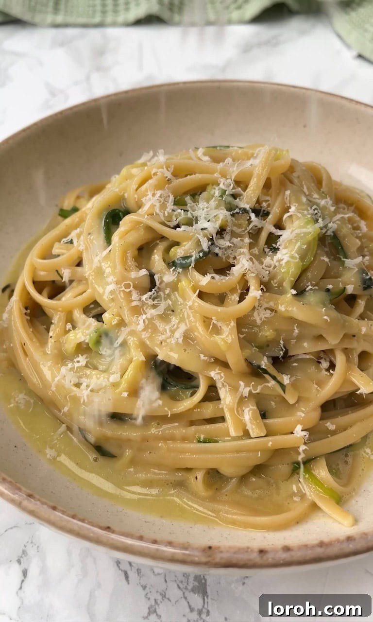 Grating additional Pecorino cheese and lemon zest over the finished Lemony Courgette Carbonara.