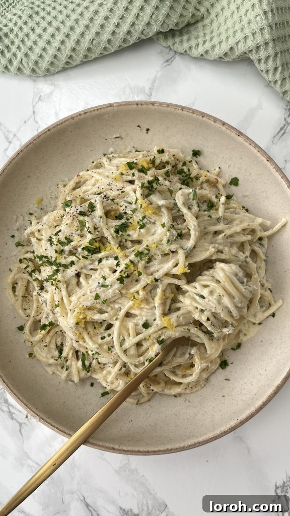 Creamy Lemon Artichoke Boursin Pasta Bake 2 A beige bowl filled with creamy Baked Boursin Pasta featuring artichokes, garnished with fresh parsley.