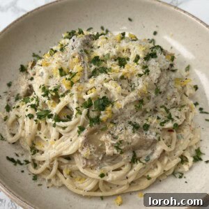 Boursin Pasta with Artichokes in a beige bowl, topped with parsley and lemon zest