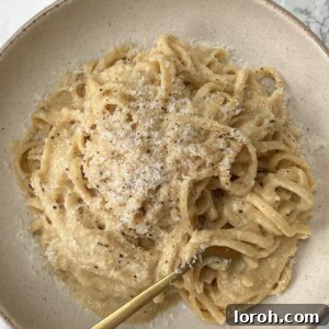 Golden Onion Brown Butter Pasta 3 A beige bowl filled with Brown Butter Pasta with Caramelized Onions and a fork