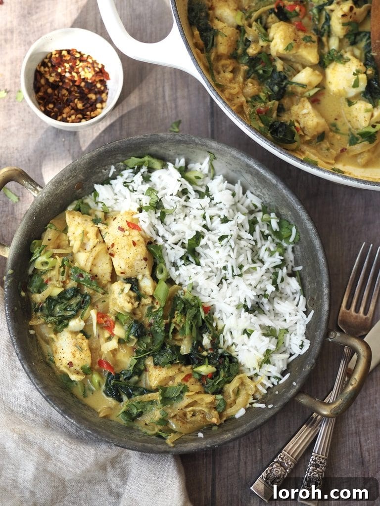 A metal serving dish of cod curry with coriander rice next to a bowl of dried chilli flakes.