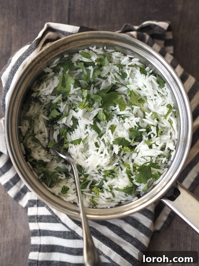 Saucepan of herby rice on top of a blue and white striped tea towel.