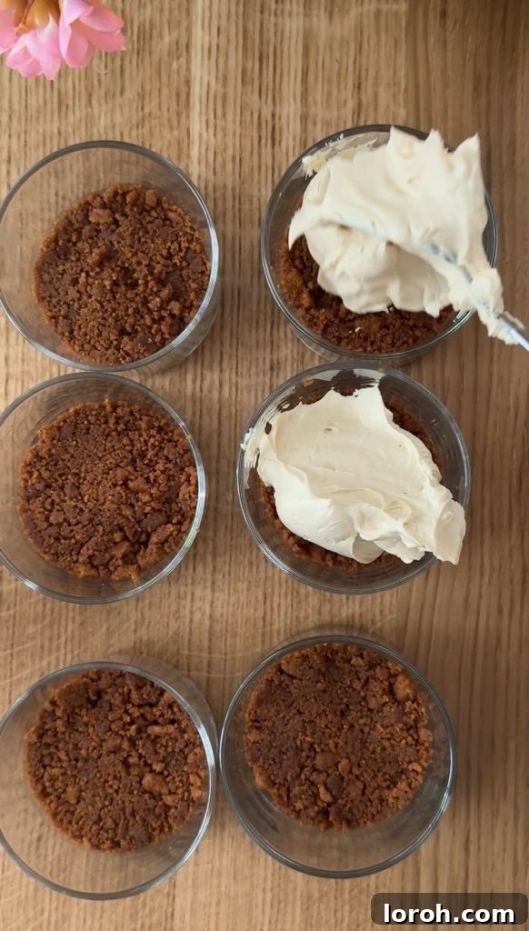 Five Ingredient No Bake Biscoff Cheesecake 7 Six cheesecake bases with the creamy Biscoff filling generously spooned on top, showcasing the assembly process.