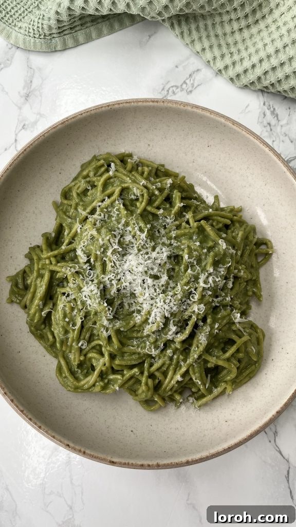 A bowl of vibrant green Ricotta Pesto Pasta, ready to be enjoyed, in a stylish beige bowl.