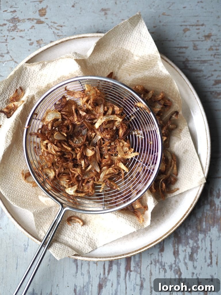 A plate with crispy shallots draining on kitchen paper.