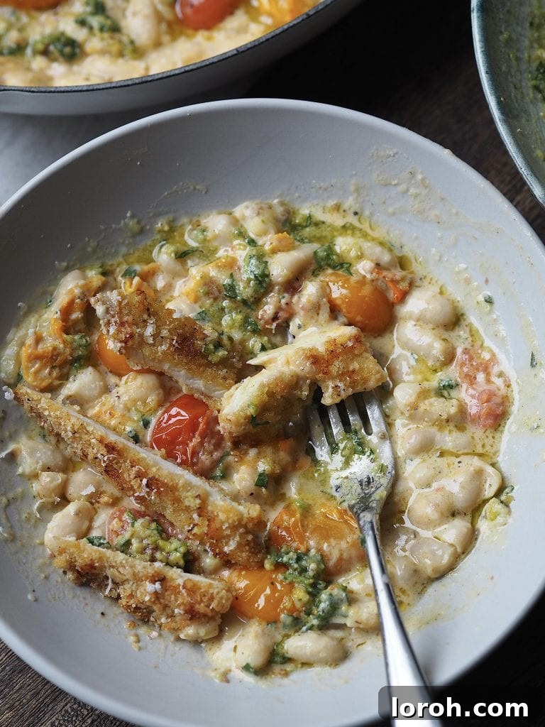 Crispy Chicken with Mediterranean White Bean Salad 2 Sliced breaded chicken breast in a bowl of white beans with tomatoes and basil.