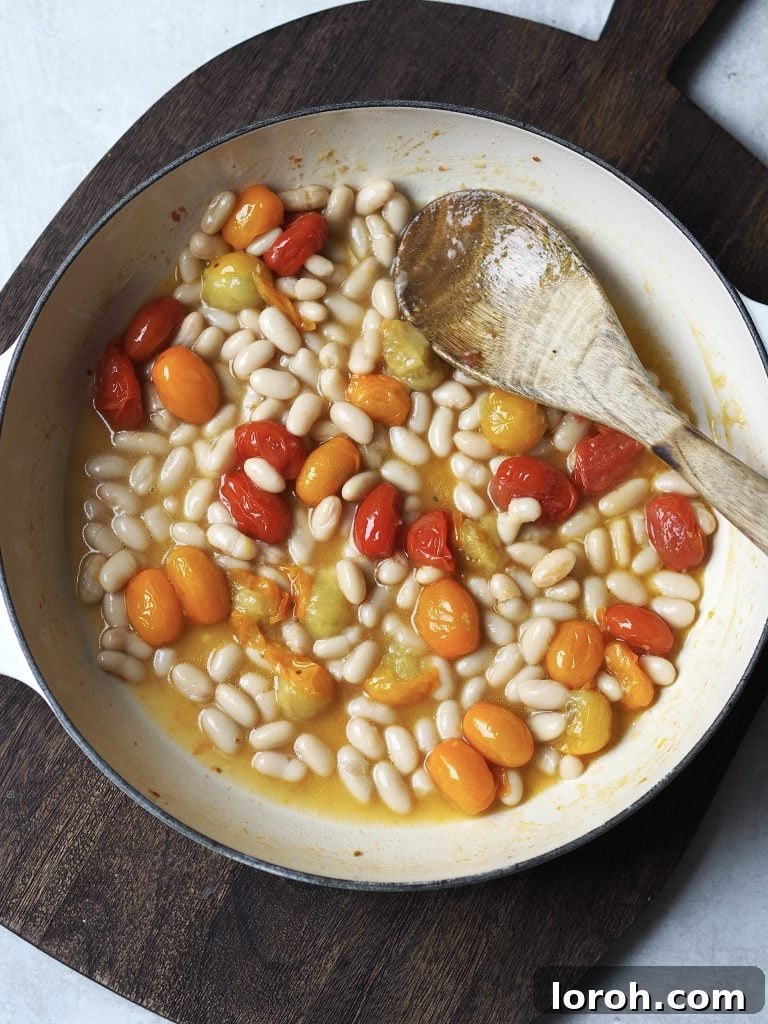 Crispy Chicken with Mediterranean White Bean Salad 5 White beans and cherry tomatoes being cooked in a shallow casserole dish.