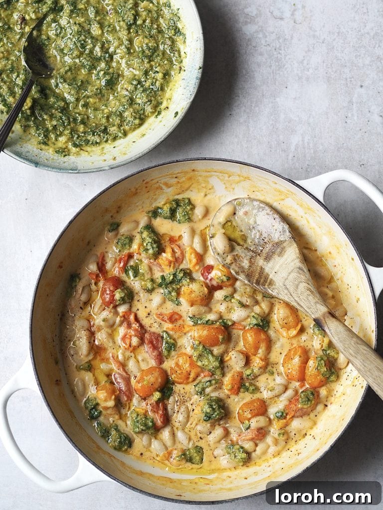 Crispy Chicken with Mediterranean White Bean Salad 6 A pan of creamy white beans cooked with cherry tomatoes drizzled with pesto, in a bowl next to the pan.