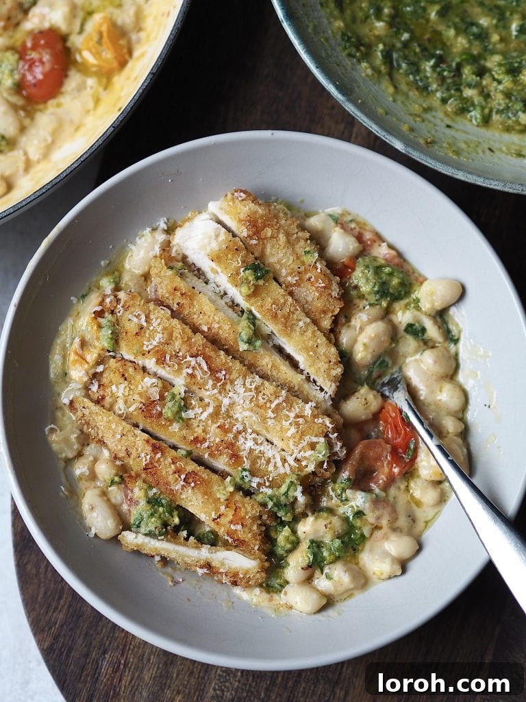 Crispy Chicken with Mediterranean White Bean Salad 9 Grey bowl of white beans and cherry tomatoes topped with a sliced crispy chicken cutlet.