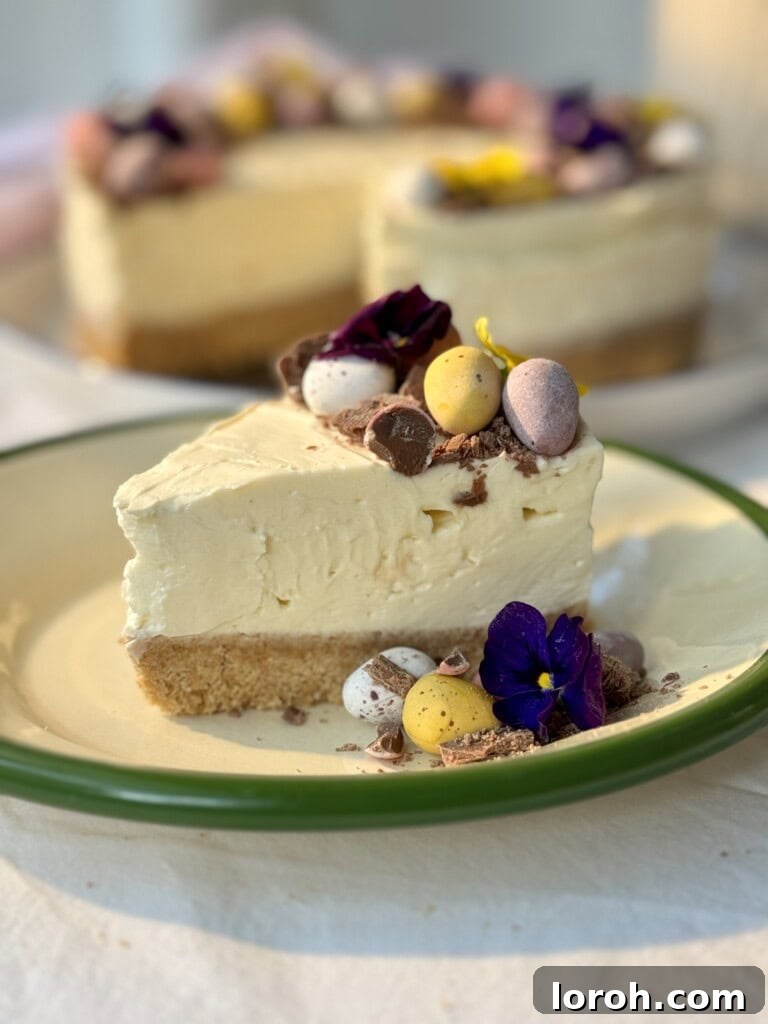 A delectable slice of Mini Egg Cheesecake on a white plate, showcasing its layers of biscuit base, creamy filling with mini eggs, and whipped cream topping.