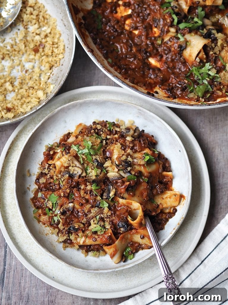 A beautifully plated bowl of vegan lentil bolognese and homemade pappardelle, ready to be garnished and enjoyed, highlighting its comforting appeal.