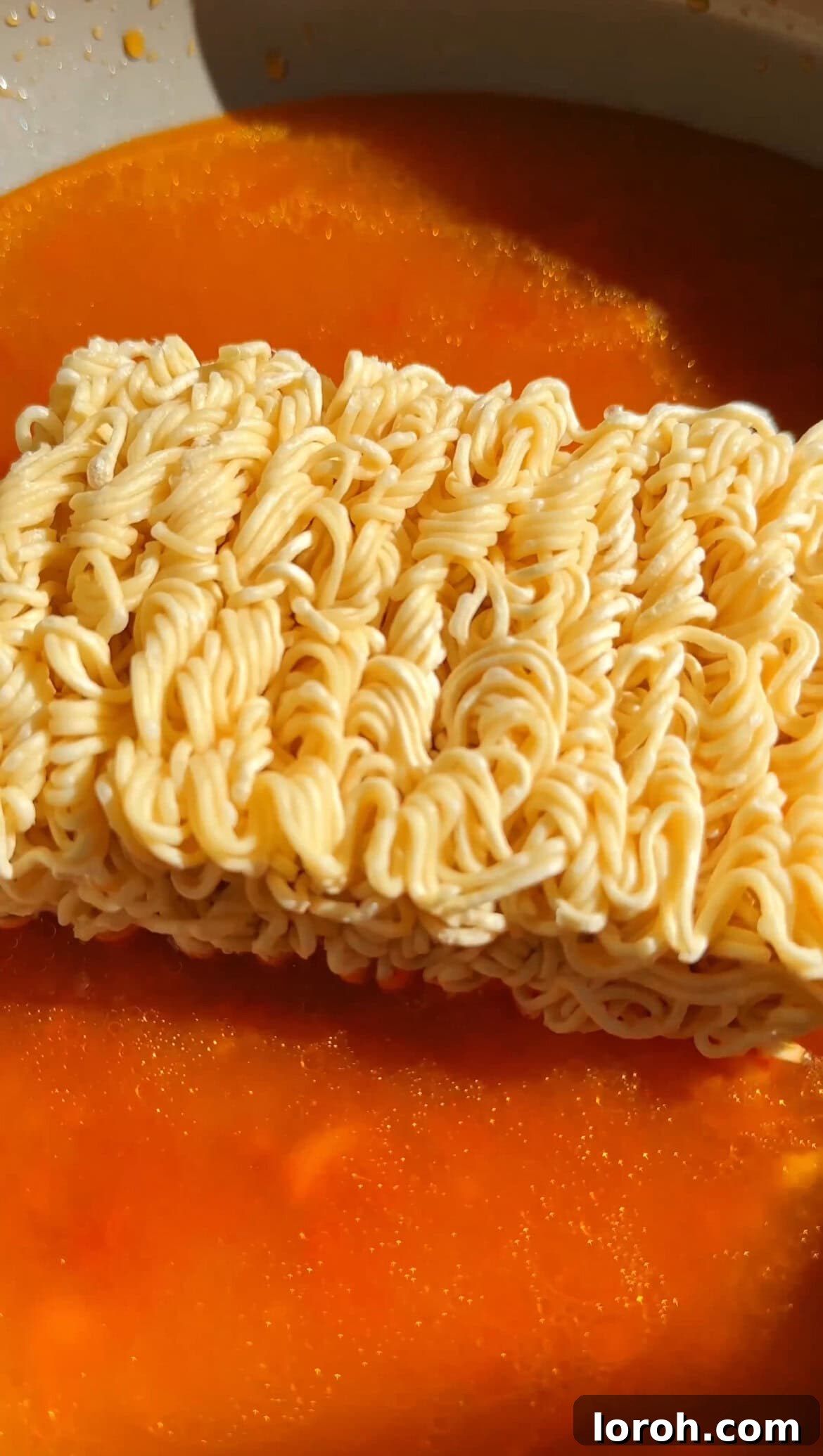 Korean Fire Cheese Noodles 6 Instant ramen noodles cooking directly in the spicy gochujang sauce, absorbing flavors as they soften.