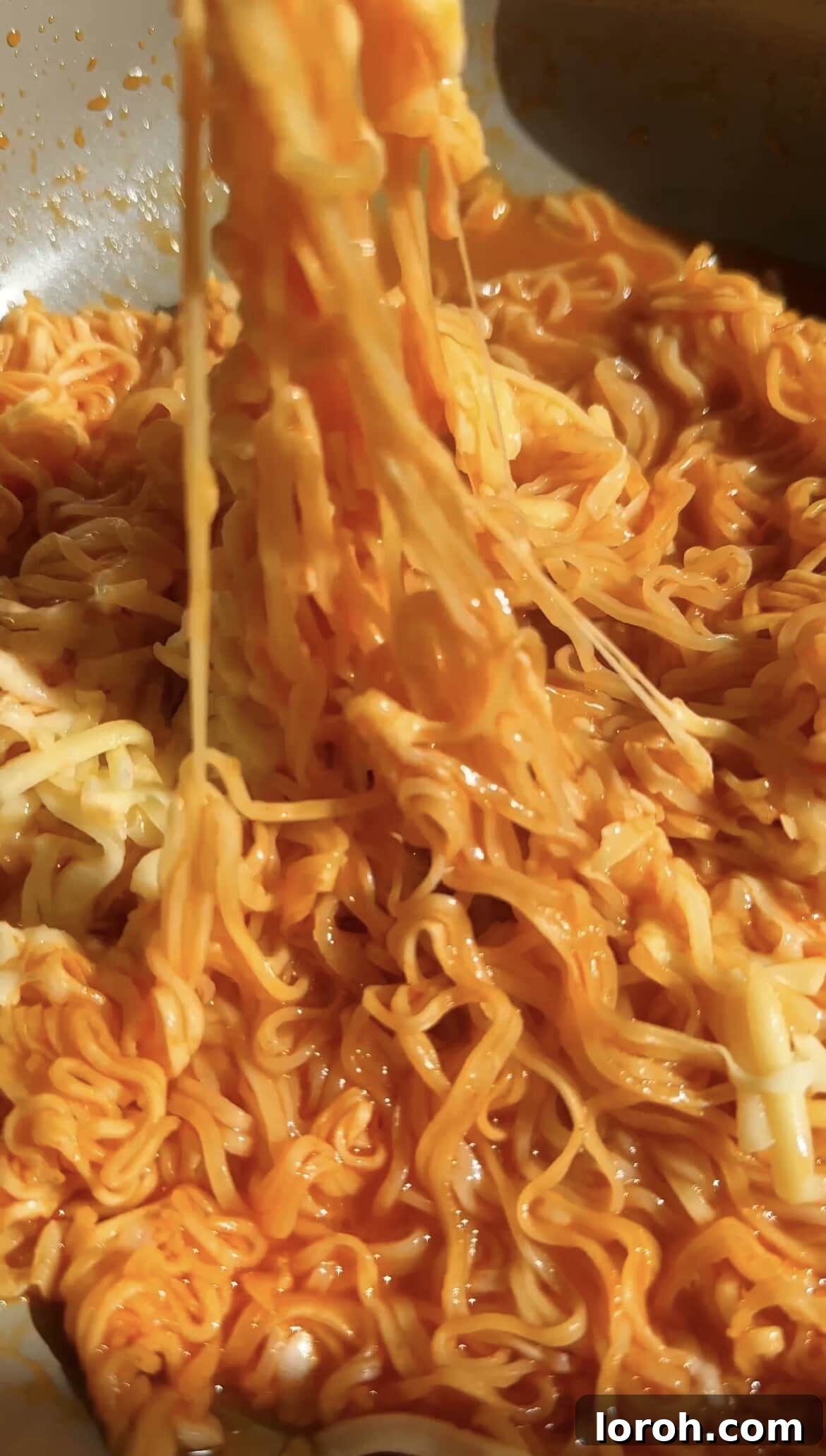 Korean Fire Cheese Noodles 9 Mixing the cheesy Korean spicy ramen noodles to combine all the delicious flavors and textures.