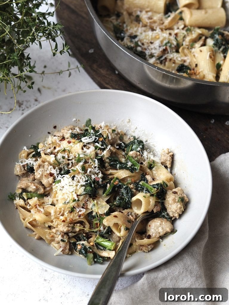Chili-Fennel Sausage Rigatoni with Tuscan Kale 3 White bowl of sausage pasta topped with grated cheese.