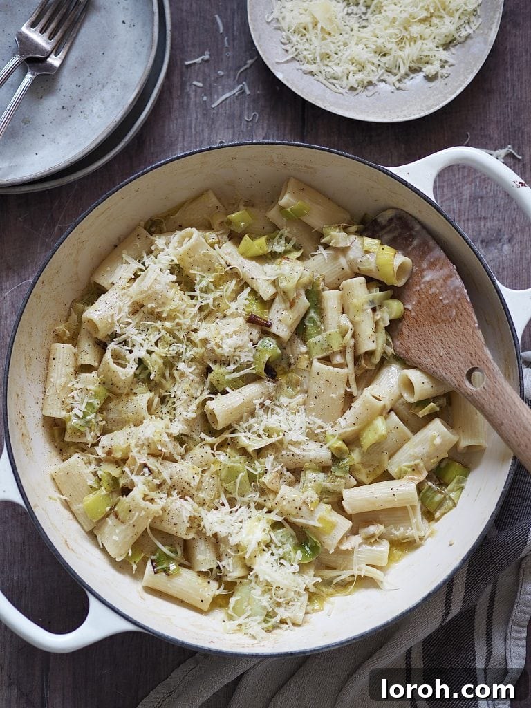 Velvety Caramelized Leek & Gruyère Pasta 3 White shallow casserole dish of rigatoni tossed with cream and caramelized leeks and topped with grated cheese.