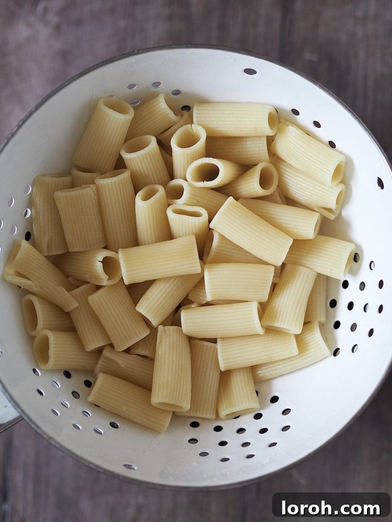 Velvety Caramelized Leek & Gruyère Pasta 5 Freshly cooked rigatoni pasta in a white colander.