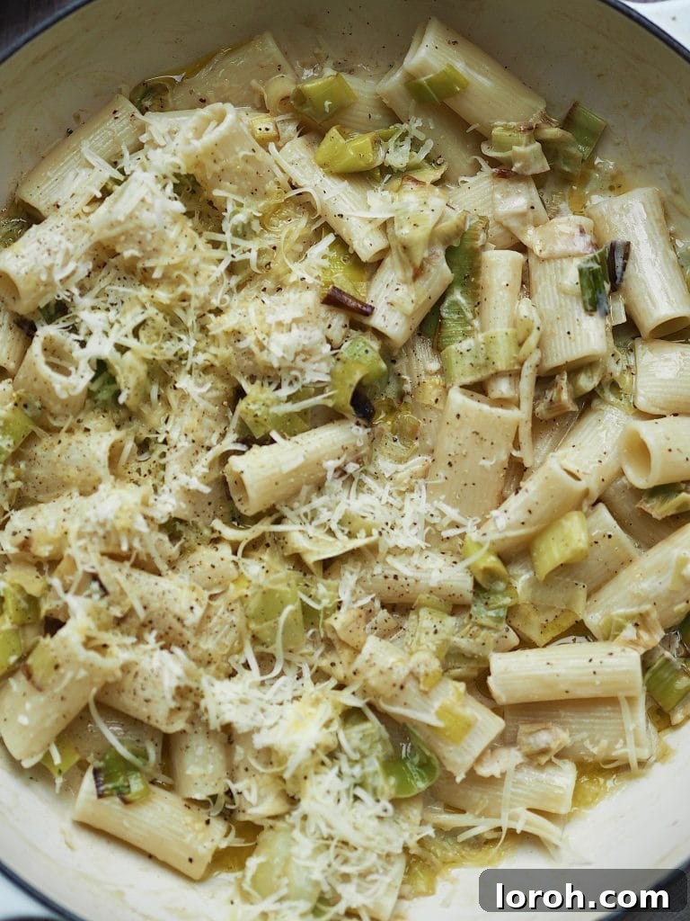 Velvety Caramelized Leek & Gruyère Pasta 9 Close up of creamy leek rigatoni in a shallow casserole topped with grated cheese.