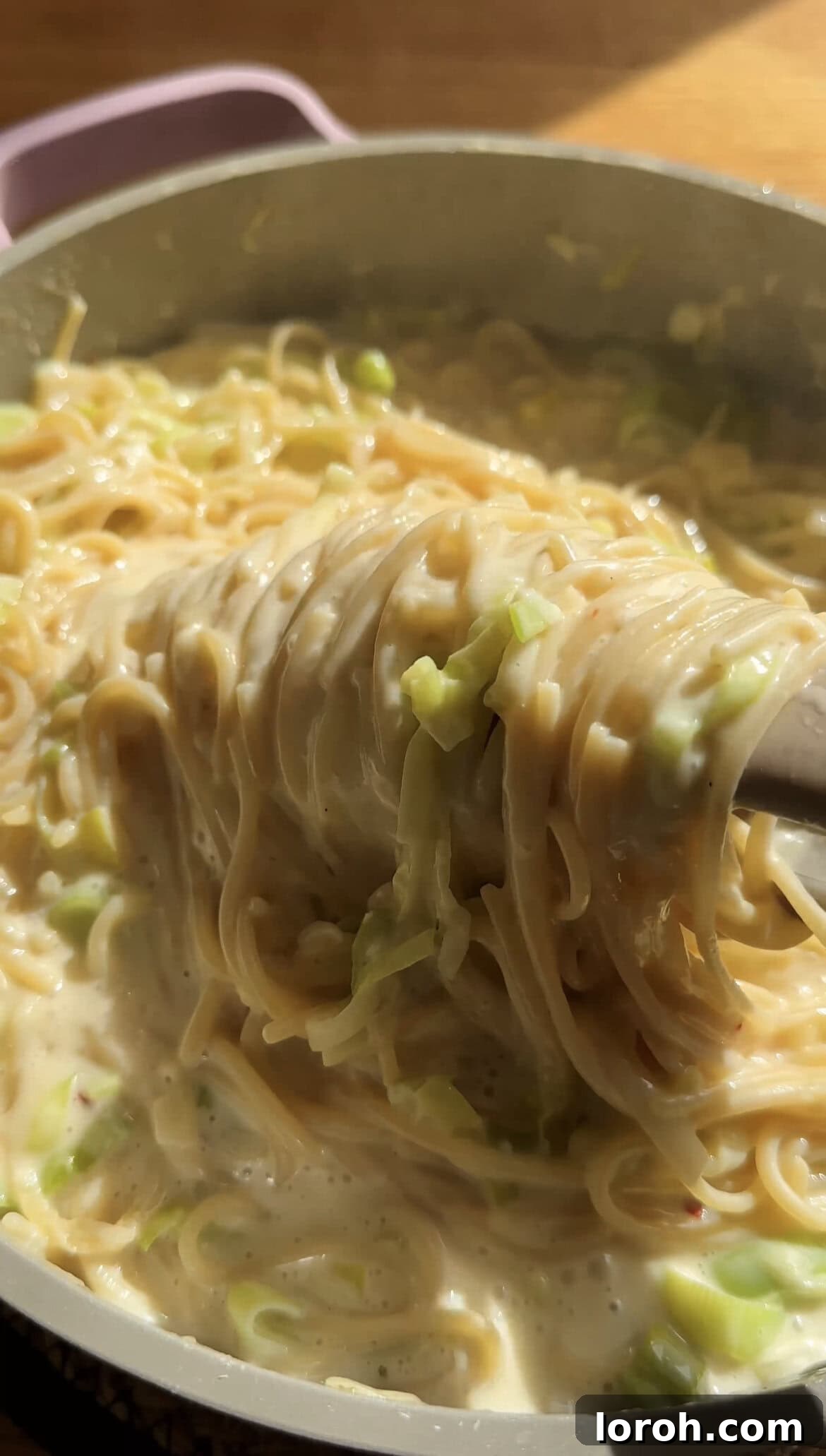 Sizzling Parma Ham & Leek One-Pan Pasta 7 Tongs twirling creamy leek pasta in a large pan, showing the rich sauce