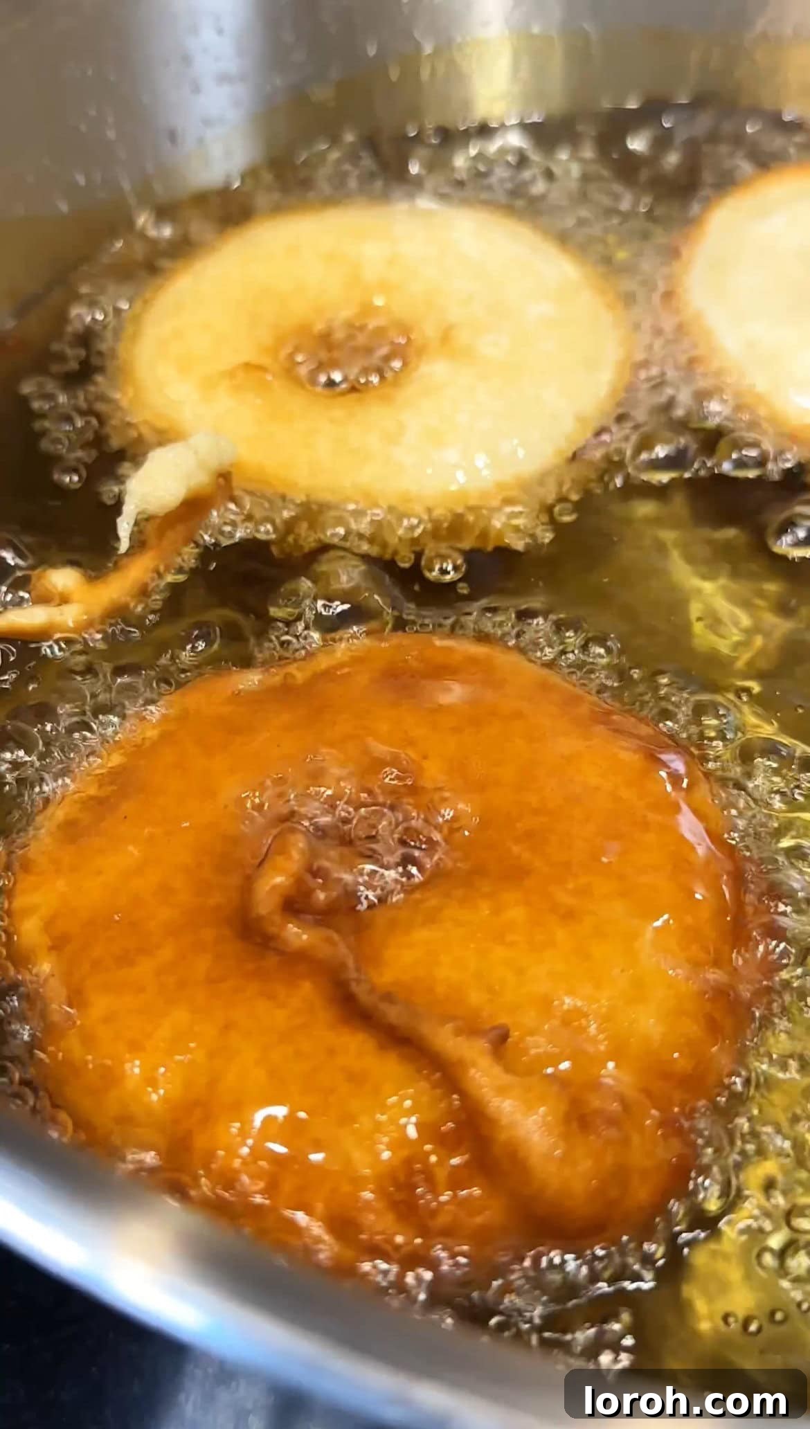 Apple Fritters 8 Apple beignets frying in hot oil until puffed and golden brown.