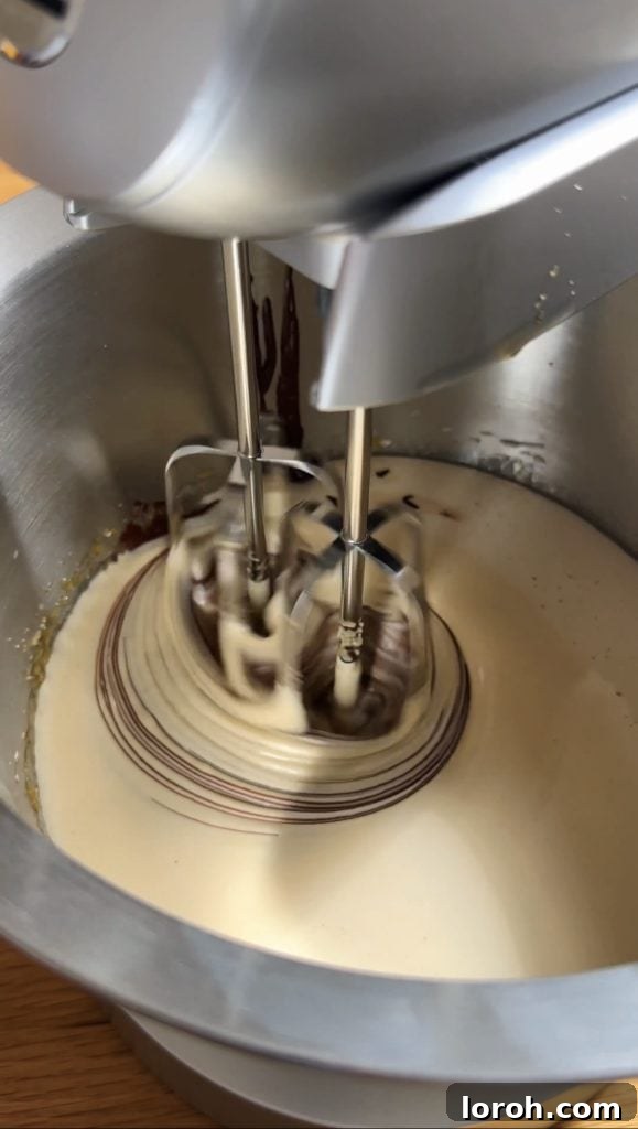 The process of adding melted chocolate and butter mixture to the whisked egg mixture, creating a rich chocolate base.
