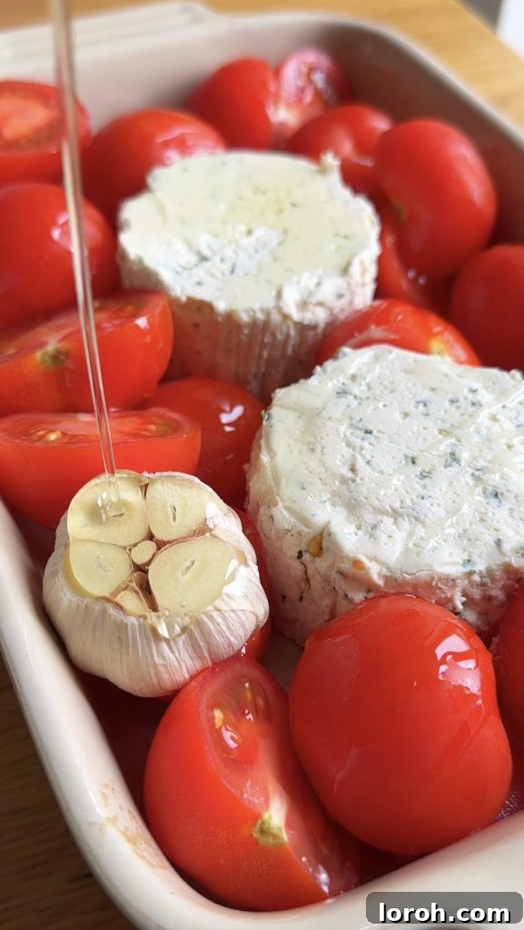 Olive oil being drizzled over a head of garlic, tomatoes, and Boursin cheese in a baking dish.