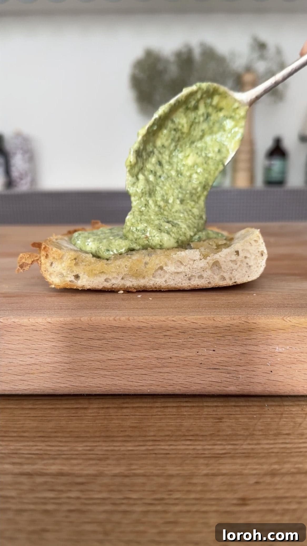 Crispy Mozzarella, Prosciutto, and Marinara Sandwich 4 Spreading a rich layer of green homemade pesto evenly onto a slice of toasted bread for a delicious sandwich.