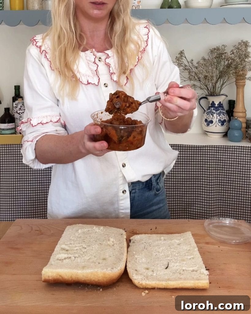 A woman holding a tub of freshly made aubergine caponata, showcasing its rich texture and vibrant colors.
