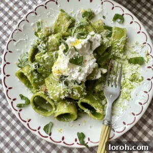 A close-up of the beautifully plated pasta in green sauce, garnished with fresh Parmesan.