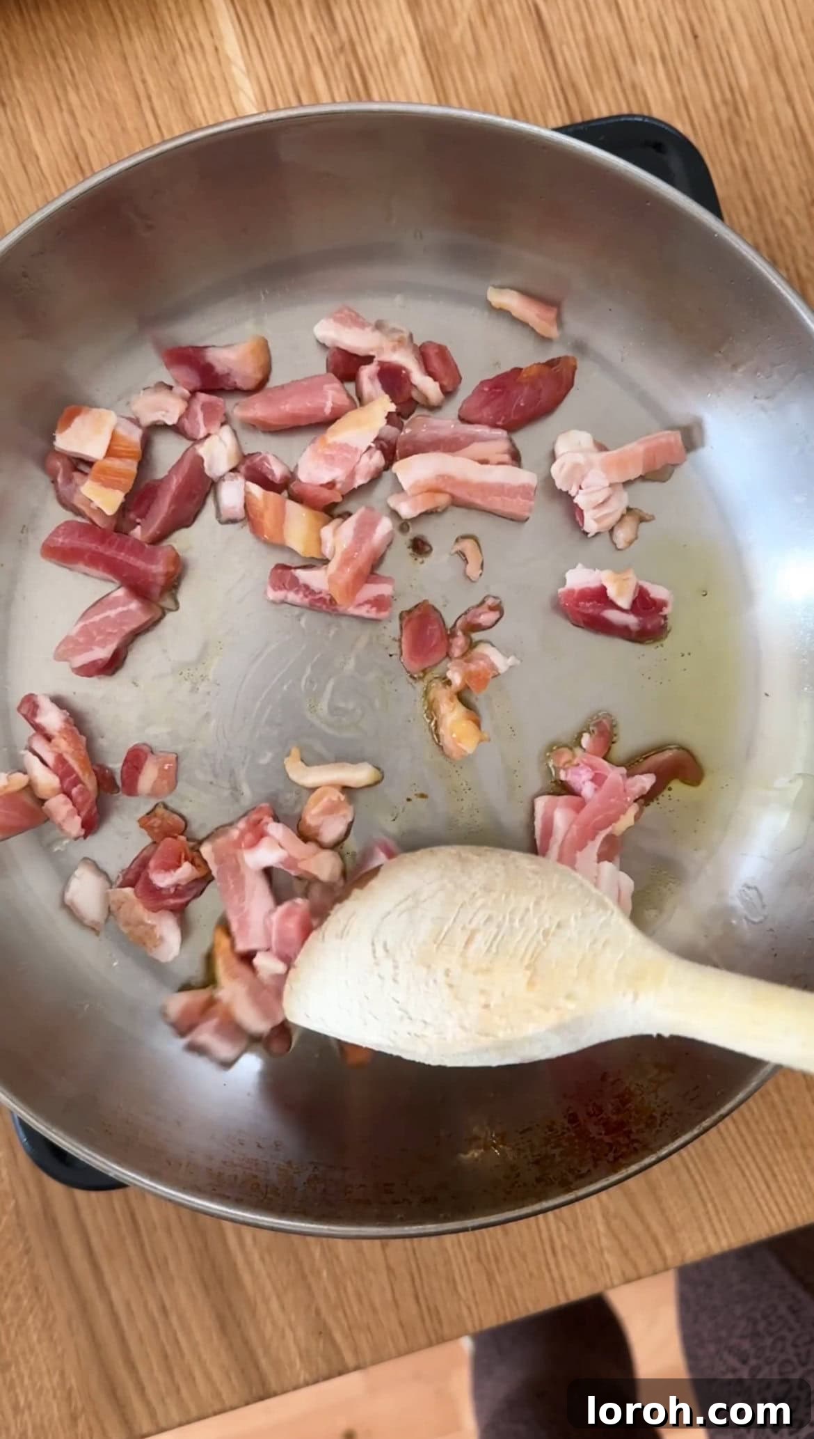 A close-up image showing pancetta sizzling and crisping up in a hot frying pan, releasing its savory fats.