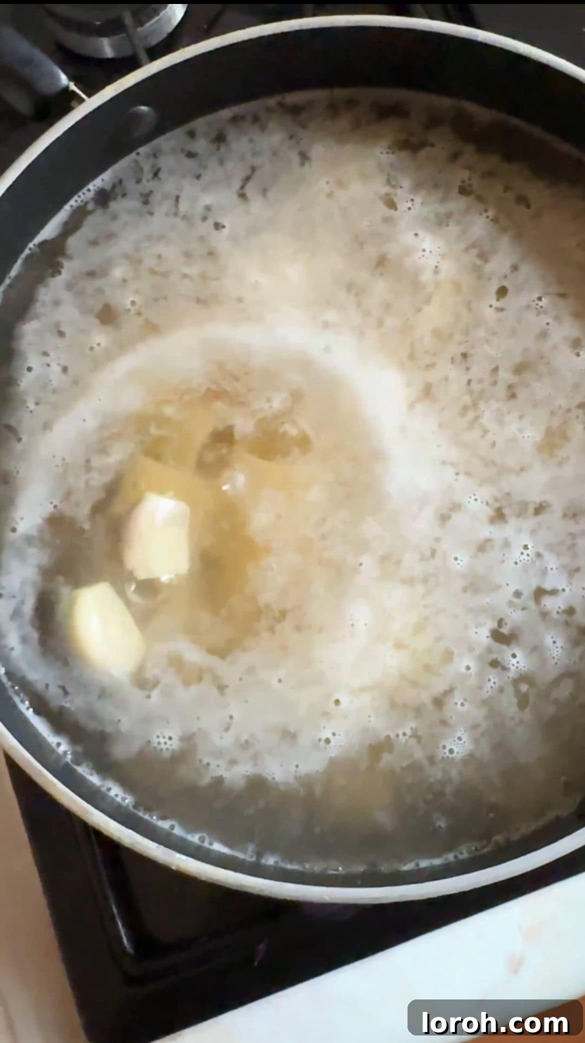 Pasta cooking in boiling salted water, with whole garlic cloves nestled among the pasta.