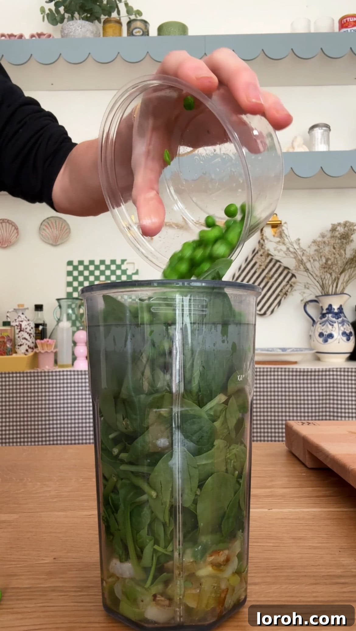 All the green sauce ingredients, including spinach, peas, basil, and Parmesan, being blended into a smooth, vibrant mixture.