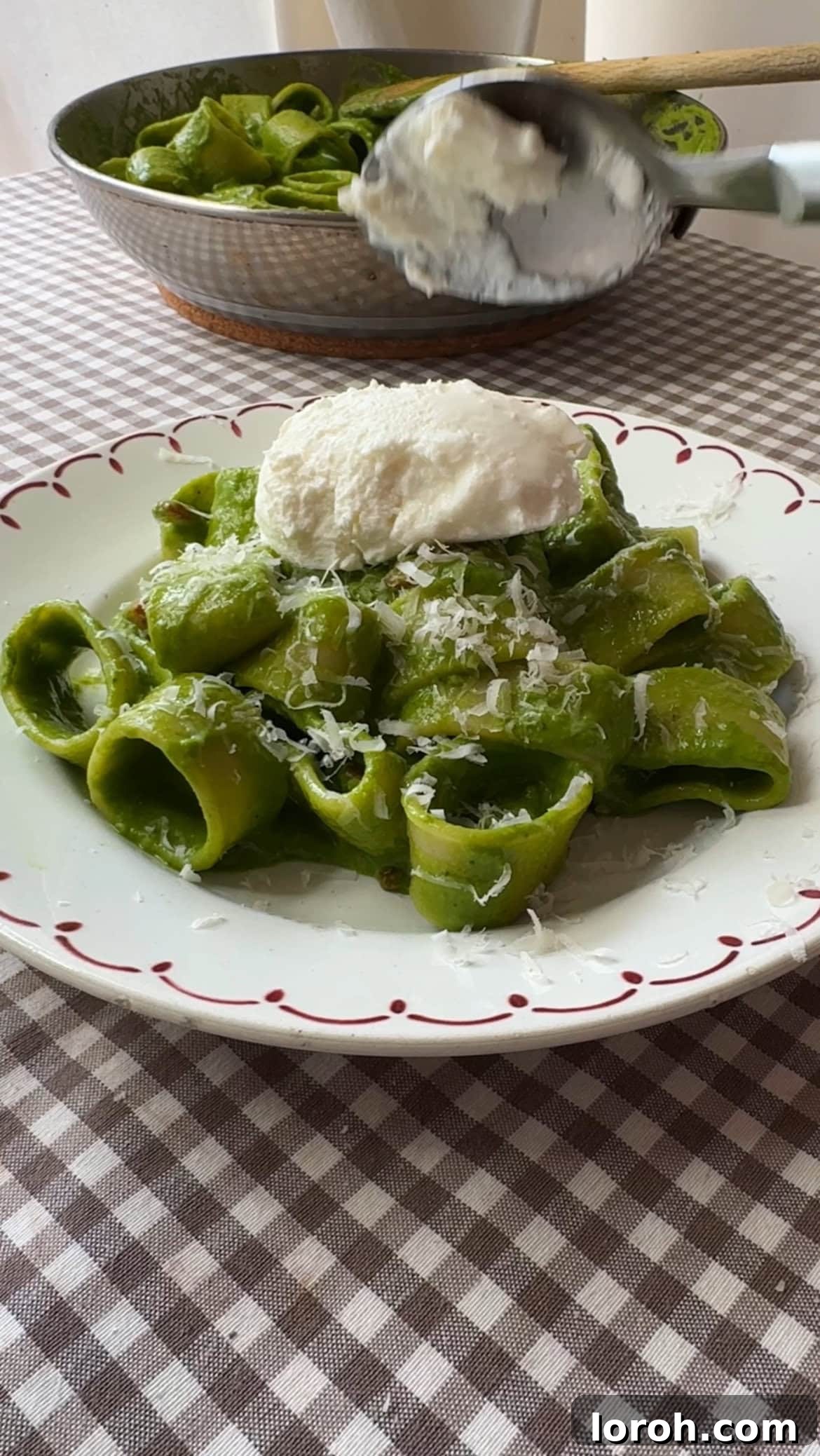 A bowl of the finished pasta in green sauce, garnished with fresh Parmesan, ready to be served and enjoyed.