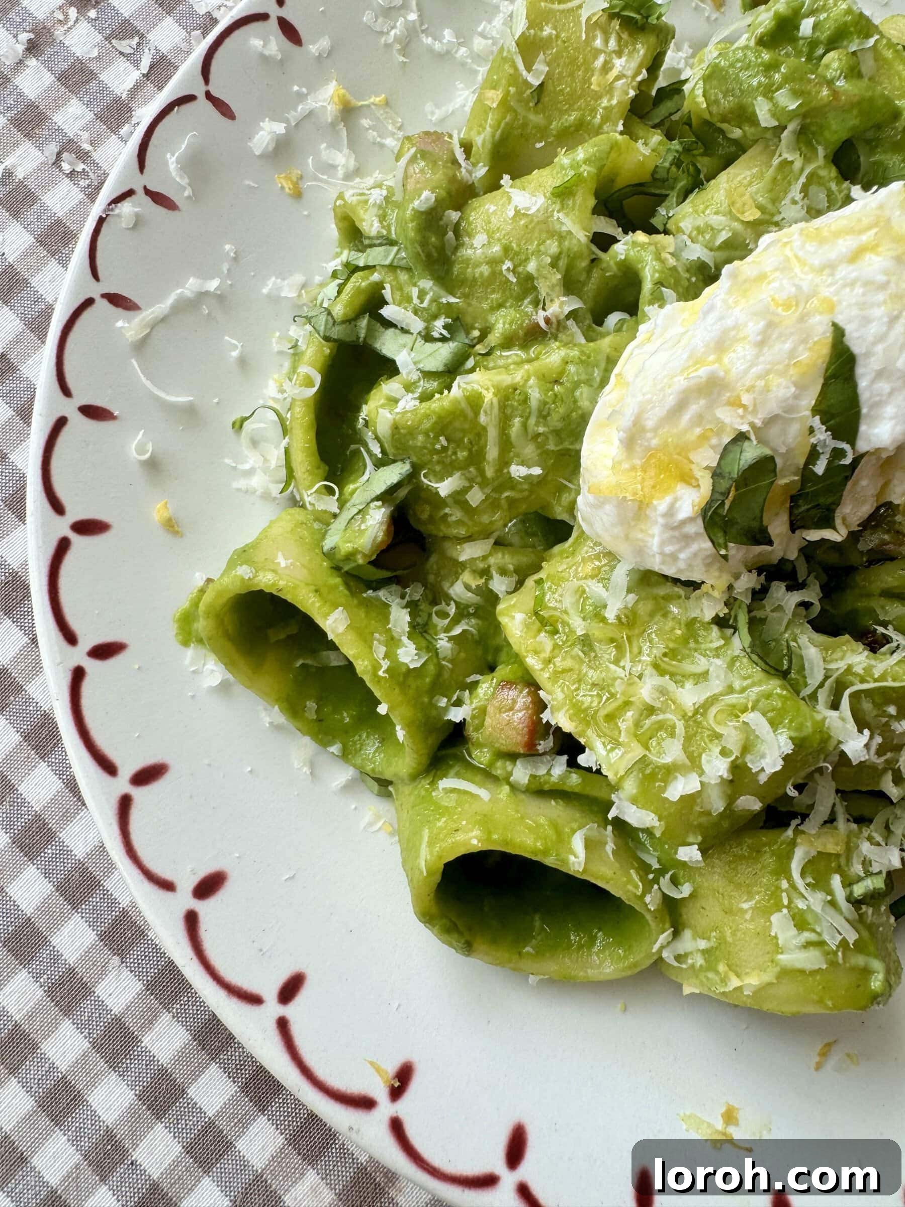 A top-down view of the vibrant green pasta, generously topped with fresh Parmesan cheese, in a stylish serving bowl.