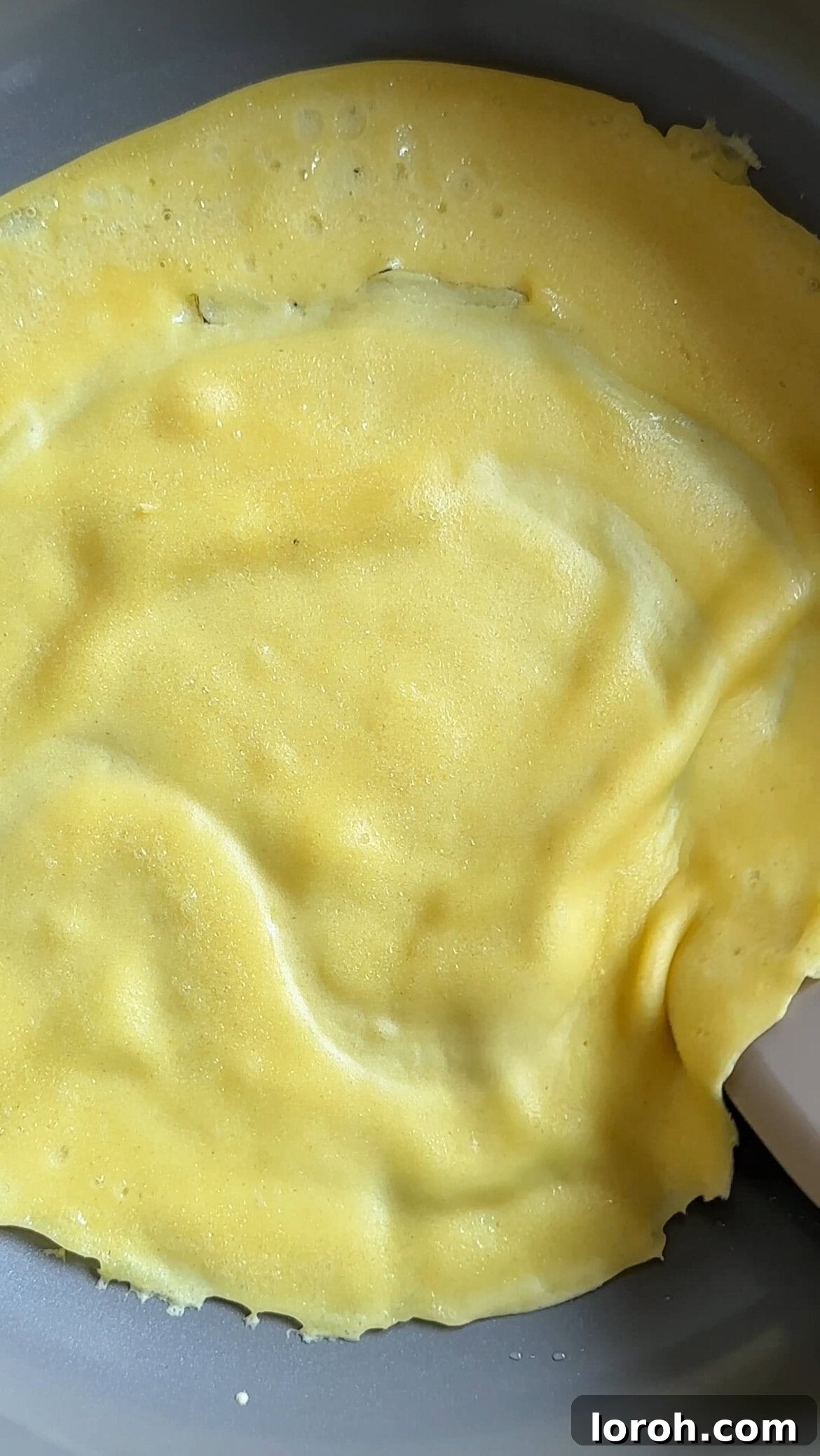 frying yellow mango pancake in a pan