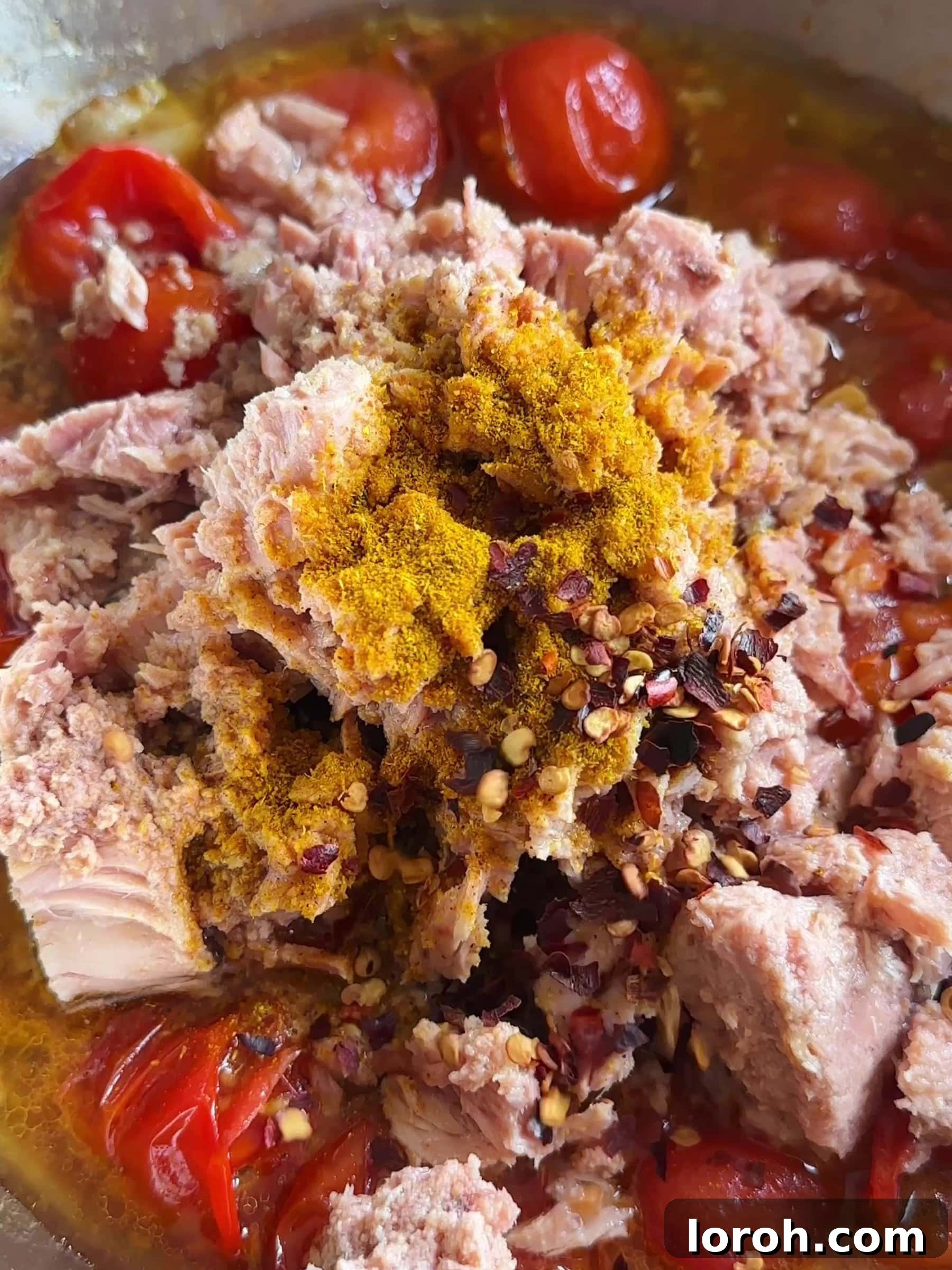 Creamy Tuna Pasta with Sweet and Spicy Tomatoes 7 Adding tinned tuna, tomato purée, curry powder, and chilli flakes to the pan.
