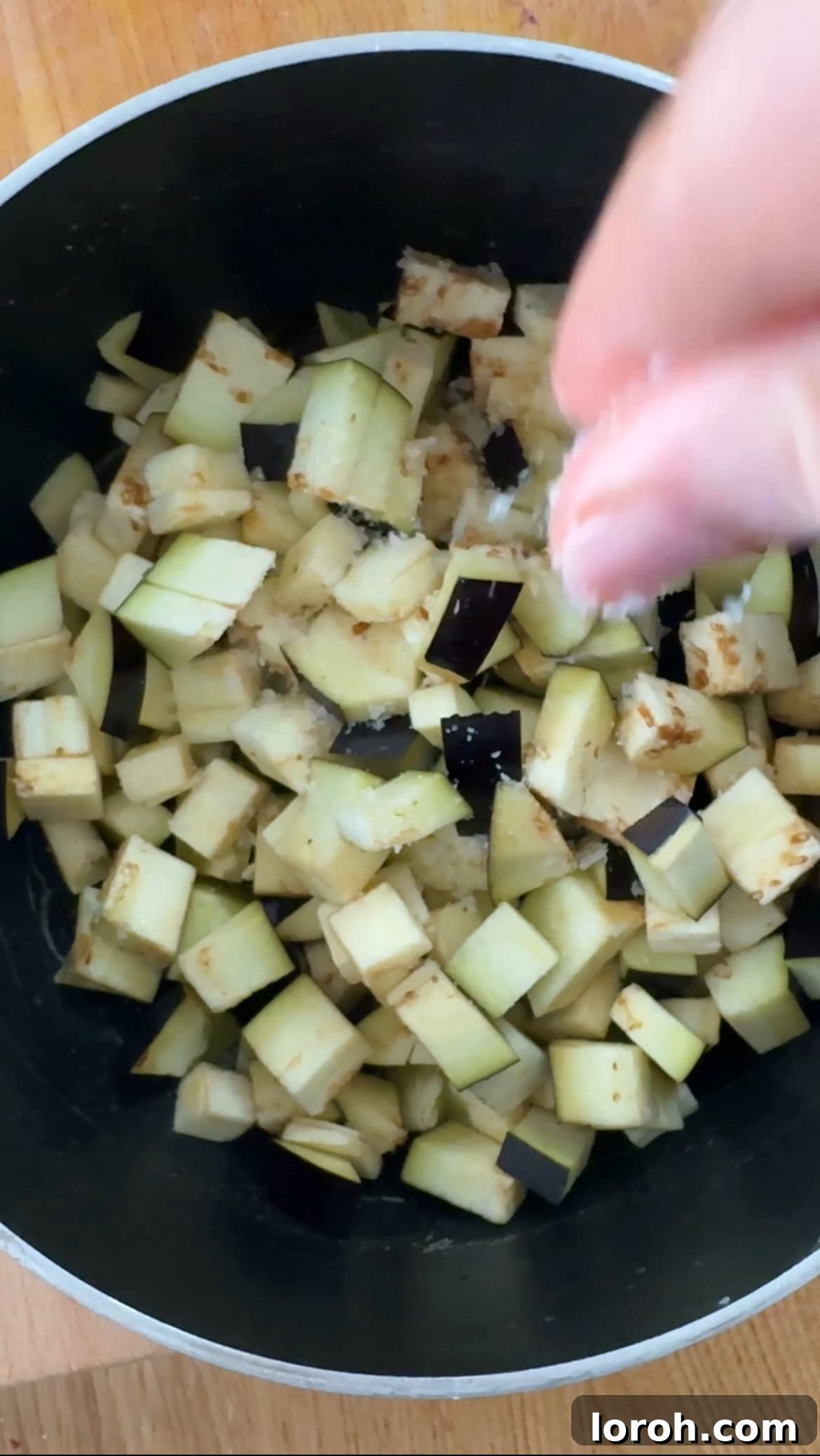 Frying diced aubergine and chopped onion in a pan with olive oil for the pasta sauce.