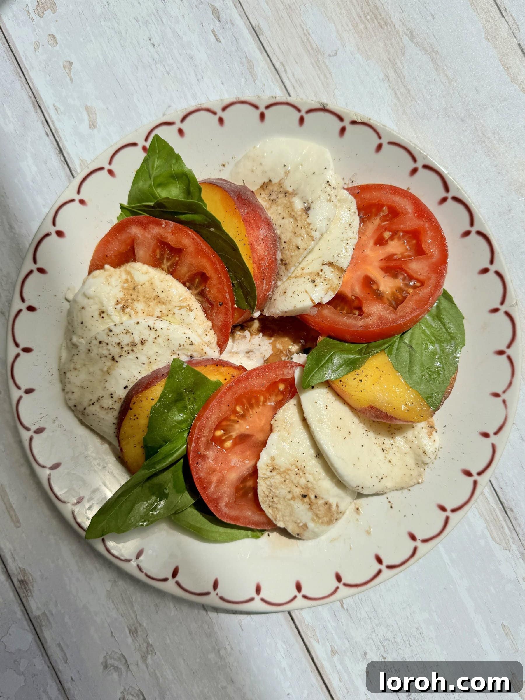 Caprese with a Peach Twist 3 Close-up of fresh, ripe peaches and tomatoes artfully arranged with creamy mozzarella and basil for a Caprese salad.